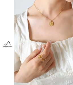 Detail einer 18K vergoldeten Edelstahlkette mit Rosenrelief und Schmetterlingsring