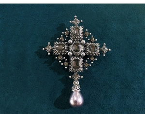 Macro detail of vintage baroque cross brooch with grey gemstones and purple pearl