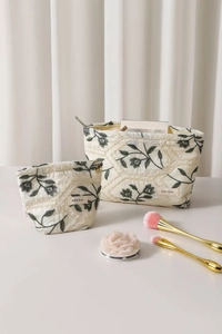 Detail of two-piece beige canvas toiletry bags with green floral embroidery and quilting