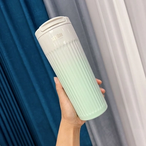 Detail of gradient green coffee tumbler with non-slip vertical texture and flip lid