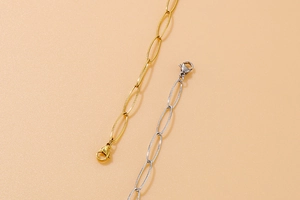 Detail of gold and silver paperclip chains with lobster clasps on beige background