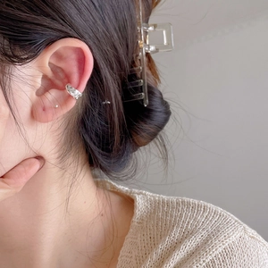Detailed view of irregular textured silver ear cuff worn on the cartilage by a model