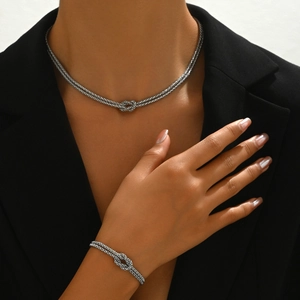 Dettaglio del set di gioielli in acciaio inox argentato con design a nodo su modella