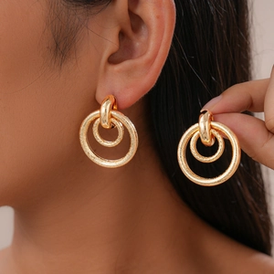 Detail of matte gold double-hoop geometric earrings with textured metal surface