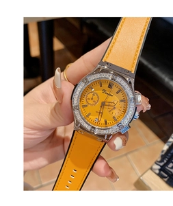 Gros plan d'une montre à bracelet jaune avec lunette sertie de strass