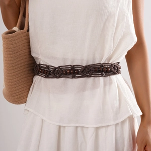 Detail of woven brown waist chain with wood beads on a white dress, bohemian style