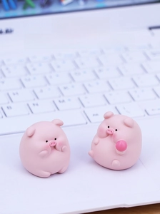 Close-up of two cute pink resin pig ornaments placed on a laptop keyboard surface