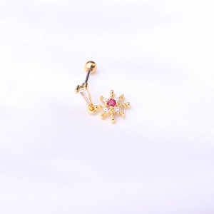 Gros plan sur piercing hélix en acier 20G avec flocon de neige et cristal rouge vif