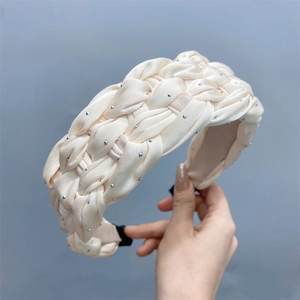 Detail of off-white braided satin headband featuring sparkling rhinestone embellishments