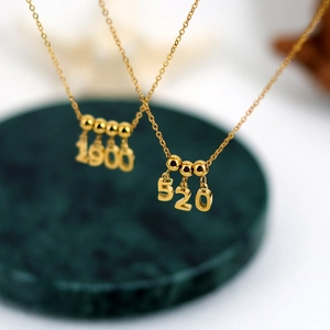 Golden DIY personalized numeric pendant necklaces 1900 and 520 on green marble