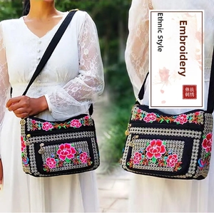 Detailed close-up of a black ethnic crossbody bag with vibrant floral embroidery and pockets