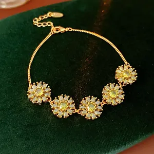 Detail of gold plated flower bracelet with yellow zircon sunflowers on green velvet