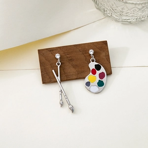 Detailed view of asymmetric earrings featuring a colorful palette and dual paintbrushes
