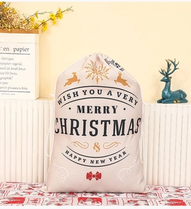 Detail of beige canvas Christmas drawstring gift bag with gold reindeer and red bow tie print