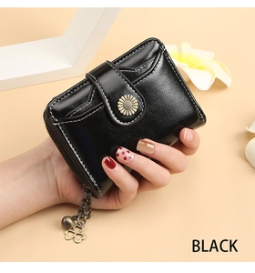 Detail of black leather wallet featuring sunflower snap button and four-leaf clover charm