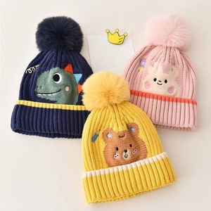 Detailed close-up of knitted baby hats with fluffy pom-poms and cute cartoon animals