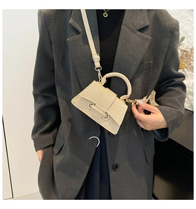 Mini sac beige à bandoulière texture tressée porté par un mannequin en blazer gris