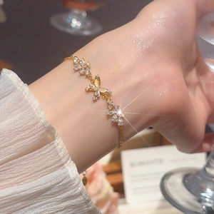 Close-up of 18k gold plated bracelet with zircon butterfly and small flower charms