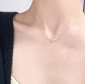 Close-up of elegant S925 silver bow pendant necklace worn on a woman's collarbone