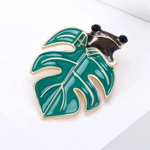 Detail of frog on leaf brooch with green enamel and gold plated metal finish