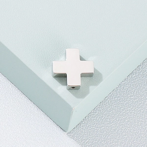 Polished silver stainless steel cross pendant on a minimalist textured blue background