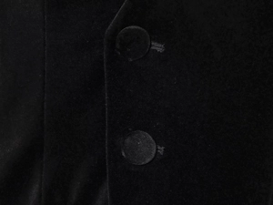 Close-up of black velvet fabric texture with matching fabric-covered buttons on romper