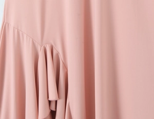 Détail du tissu rose montrant les coutures et la conception plissée de la robe