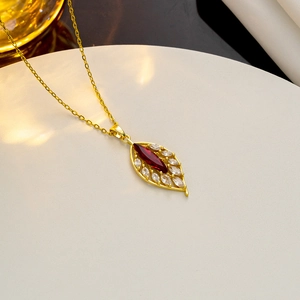 Macro shot of gold necklace featuring red marquise gem surrounded by white cubic zirconia