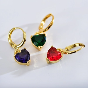 Macro shot of three gold hoop earrings featuring purple, green, and red heart gemstones