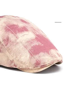 Detail of red tie-dye newsboy cap showing the foldable wide brim and textured fabric