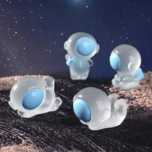 Set of four luminous resin astronaut figurines with blue visors on a moon surface