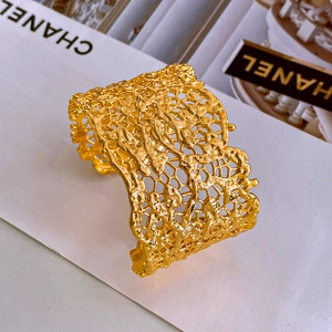 Macro detail of wide gold-plated cuff featuring organic lava cutout texture and shiny finish