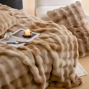 Detailed texture of light brown plush blanket and matching pillow with wave pattern