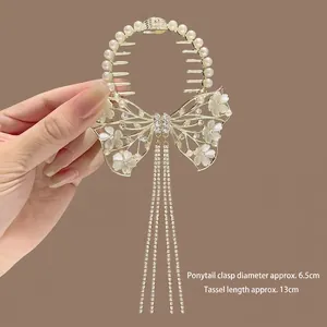 Détail de la pince à cheveux papillon dorée avec perles de muguet et longs glands