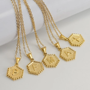 Gold plated hexagon initial necklaces with P F M A X letters on a white background