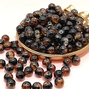 Close-up of 10mm dark brown crackle glass beads for DIY jewelry making in a gold tray