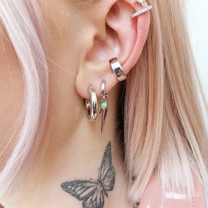 Detail of silver S925 earrings set with green opal and spikes on a female model