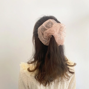 Pink polka dot lace scrunchie made of light tulle worn on a ponytail for women