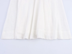 Detailed close-up of white eyelet embroidery lace fabric on the midi dress hemline