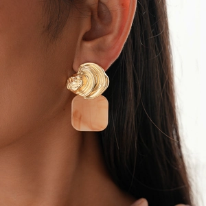 Close-up of gold irregular texture metal and square marble resin pendant earrings