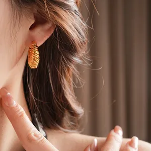 18k gold plated hoop earrings with spiral texture shown on model in warm lighting