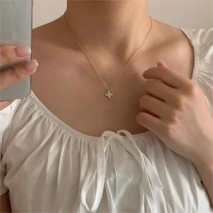 Macro view of dainty gold cross necklace with small sparkling zircon stones on model