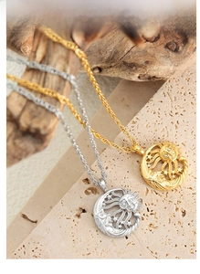 Detail of sun pendant necklaces with zircons on travertine stone and wood background