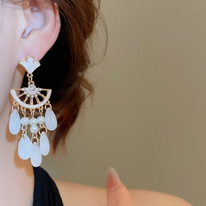 Close-up of elegant gold ginkgo leaf earrings with pearl tassels and crystal accents