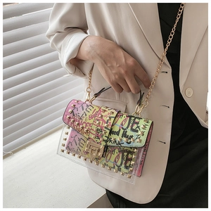 Detail view of graffiti print jelly bag with gold rivets and chain strap on a model