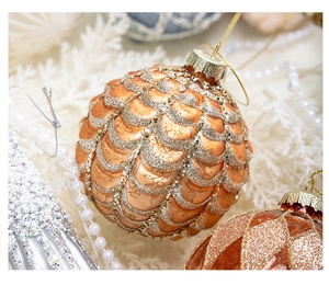 Macro view of an orange gold Christmas bauble with glitter scale patterns and gold string