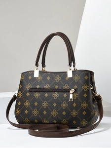 Detailed view of brown handbag with vintage monogram print and golden metal hardware