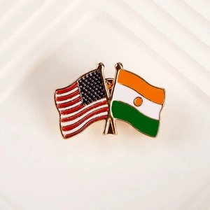 Detail of metal badge featuring crossed USA and Niger flags with gold-plated borders