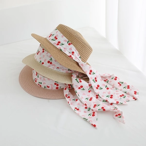 Detail of stacked straw sun hats featuring elegant cherry print chiffon ribbon ties