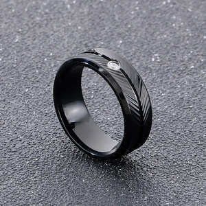 Macro shot of black stainless steel ring with feather engraving and inset zircon stone
